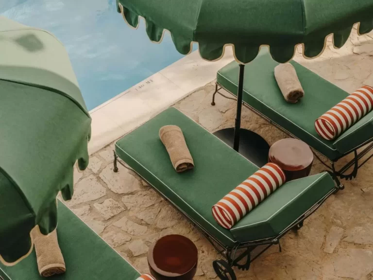 Área de descanso junto a piscina en Mallorca con camastros verdes y sombrillas de tela ondulada