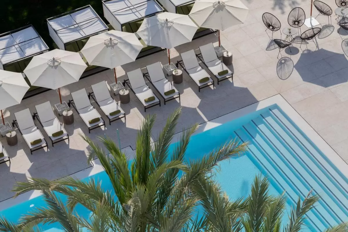 Área de piscina al aire libre con camastros, sombrillas blancas y sillas metálicas modernas en Mallorca
