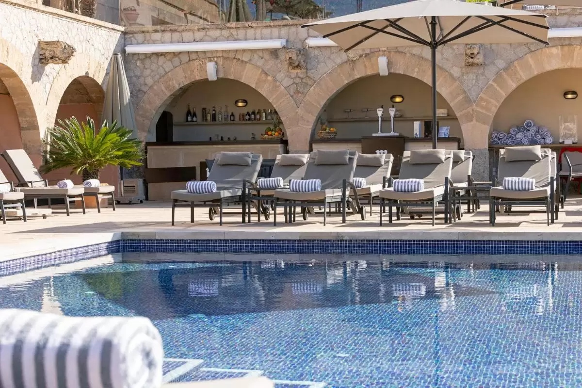 Hospes Maricel y Spa, Palma de Mallorca, a Member of Design Hotels Área de piscina exterior en Mallorca con tumbonas acolchonadas, sombrillas y barra con arcos de piedra