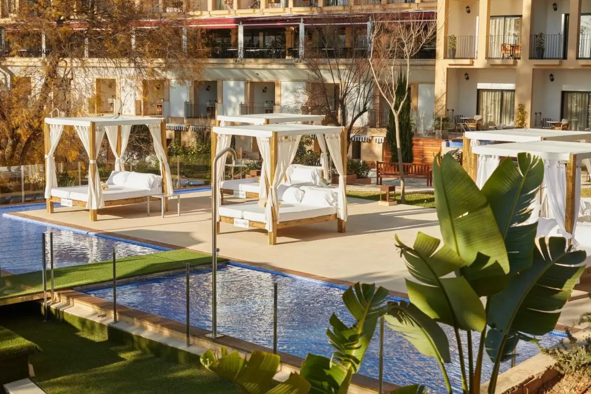 Área exterior con piscina alargada, camas balinesas y barandales de vidrio en entorno residencial en Mallorca