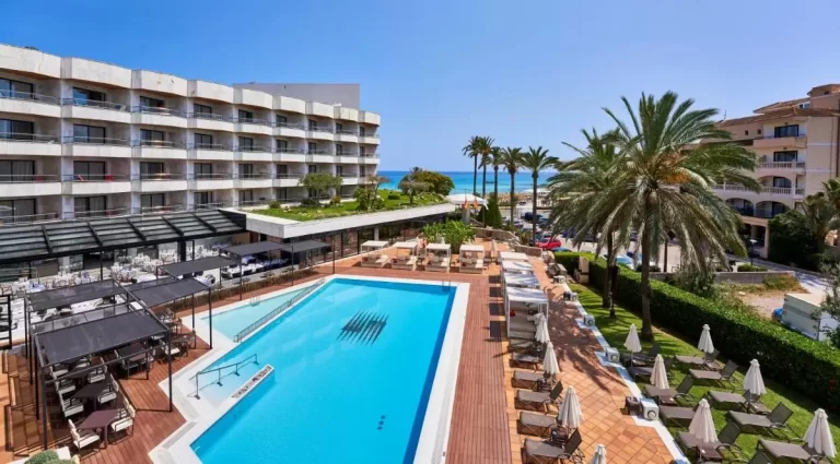 Área exterior con piscina, deck de madera, zona de comedor cubierta y vistas al mar en Mallorca