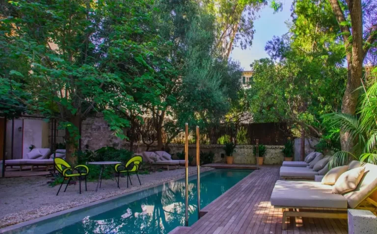 Área exterior con piscina rectangular, deck de madera, tumbonas acolchonadas y vegetación en Mallorca