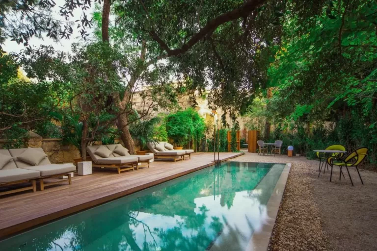 Área exterior con piscina rectangular, deck de madera, tumbonas acolchonadas y vegetación en Mallorca