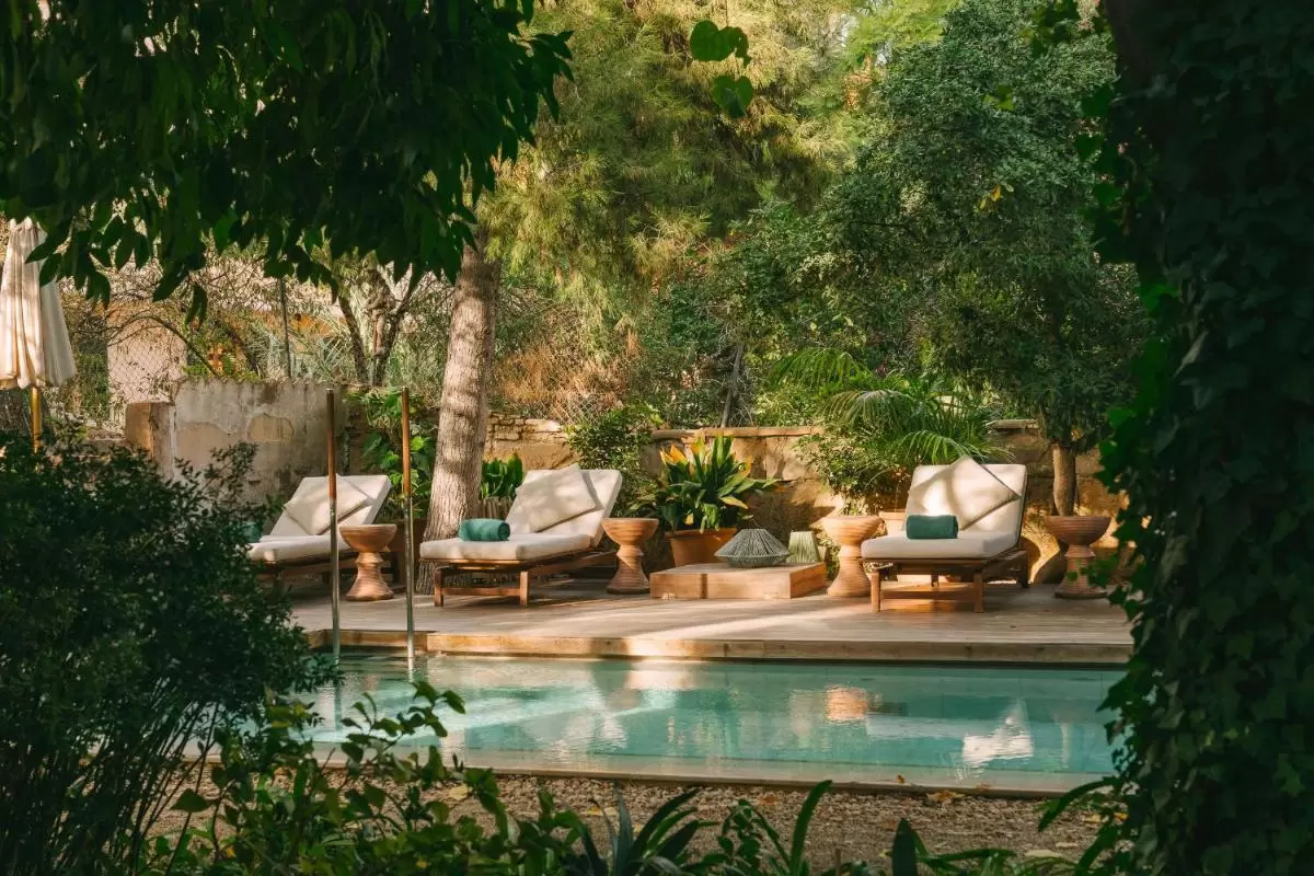 Área exterior con piscina rectangular y deck de madera clara rodeada de vegetación en Mallorca