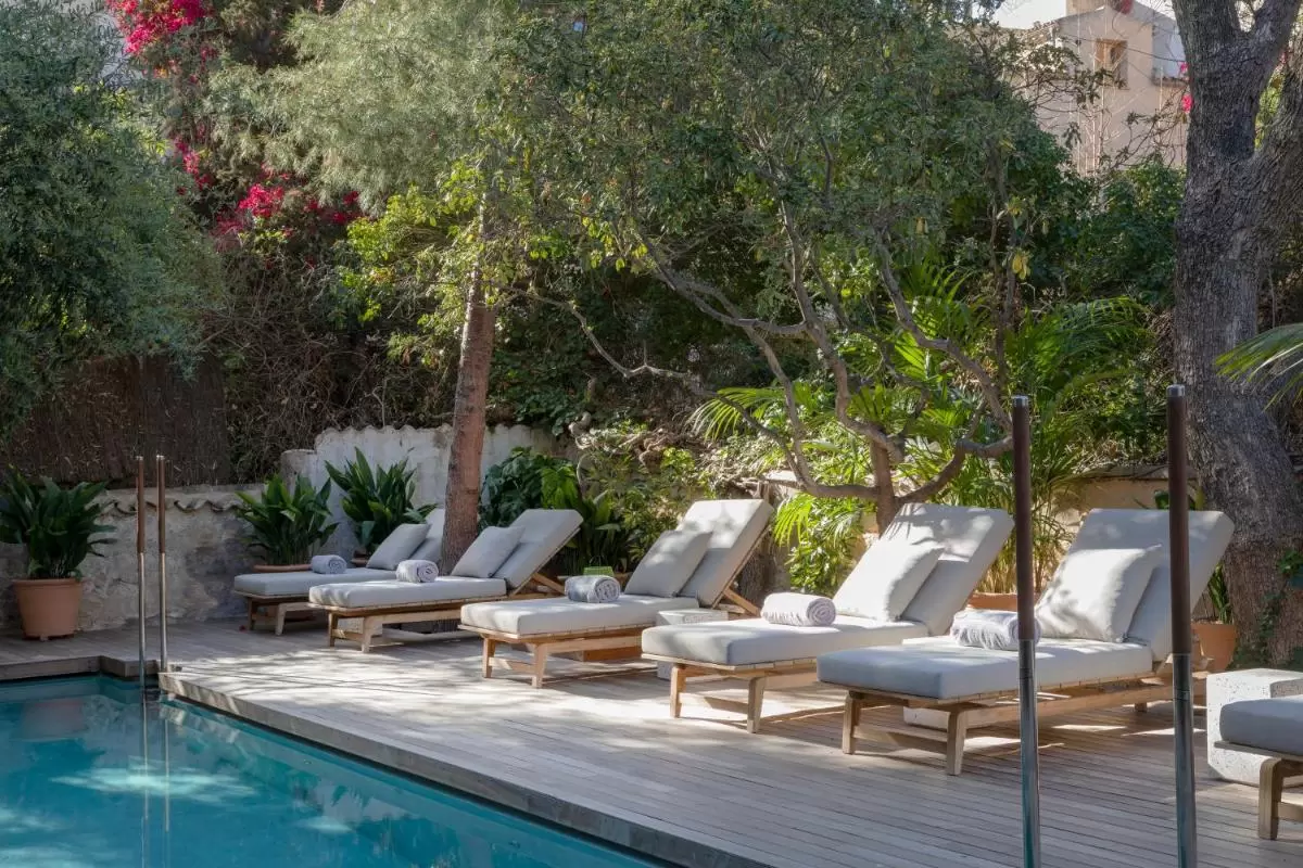 Área exterior con piscina y tumbonas de madera clara en entorno natural para relajación en Mallorca