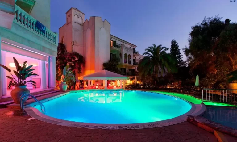 Área exterior nocturna con piscina ovalada iluminada y zona de descanso con toldo blanco en Mallorca