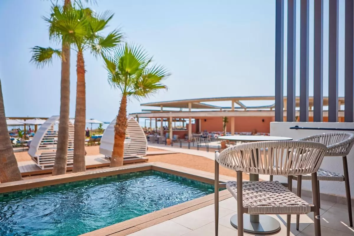 Área recreativa exterior con piscina, palmeras y mobiliario moderno en entorno costero de clima cálido en Mallorca