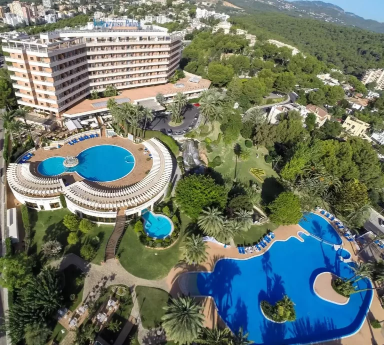 Complejo con múltiples piscinas y áreas verdes en Mallorca con diseño arquitectónico en forma de L y terrazas con tumbonas