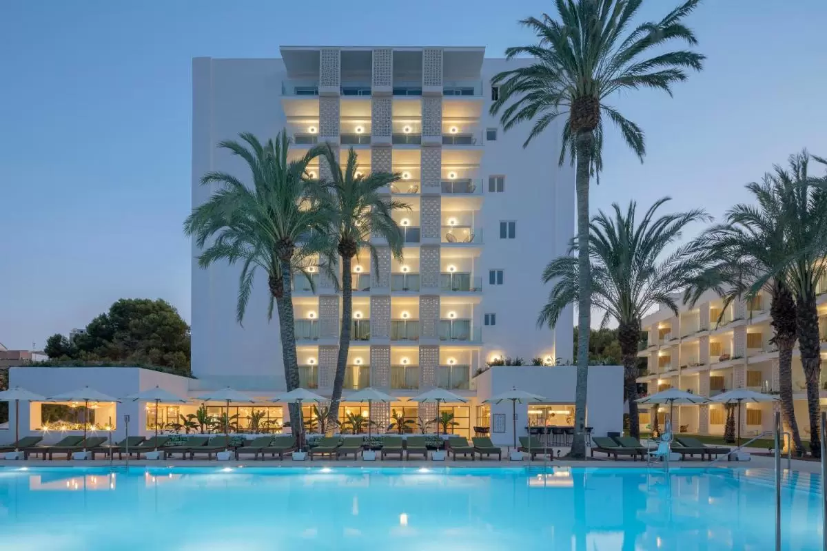 HM Ayron Park - Adults Only Complejo residencial con piscina iluminada y balcones modernos en entorno tropical al atardecer en Mallorca