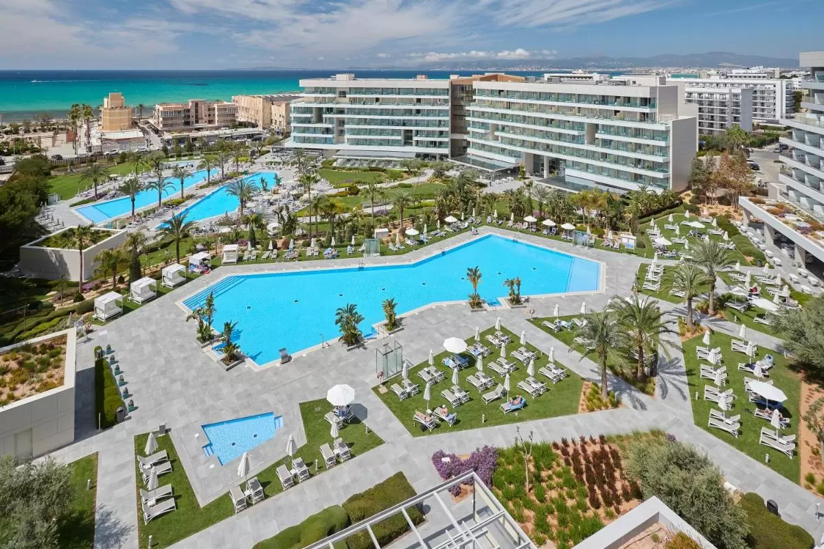 Complejo residencial en Mallorca con múltiples piscinas al aire libre, áreas verdes y vistas al mar turquesa