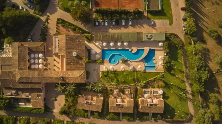 Complejo residencial en Mallorca con piscina irregular, áreas verdes, terrazas y canchas deportivas al aire libre