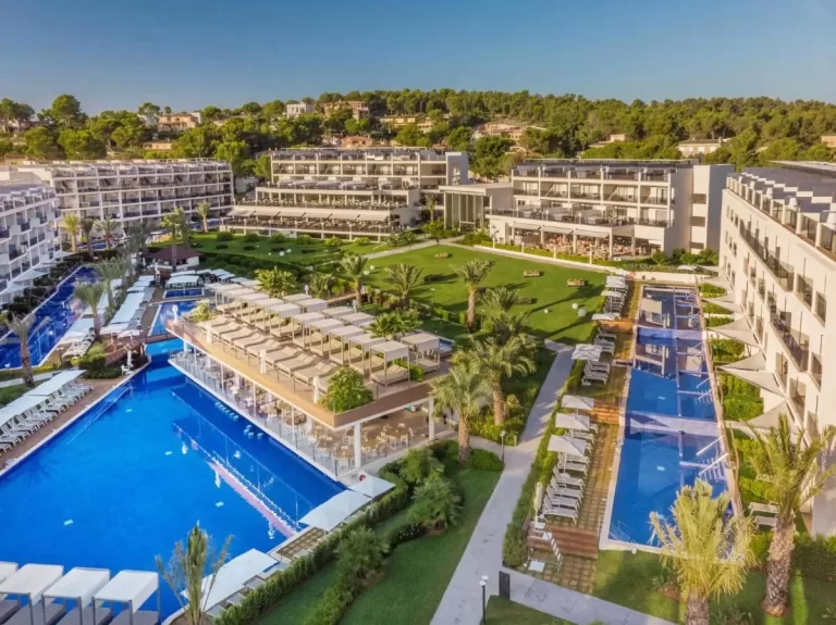 Complejo residencial moderno en Mallorca con piscinas, áreas verdes y entorno natural con colinas y palmeras