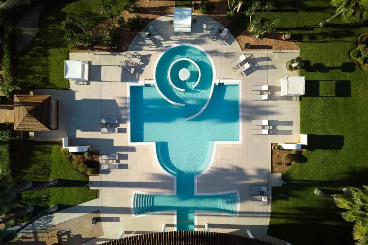 Diseño arquitectónico de piscina con tobogán espiral y área de descanso en entorno ajardinado en Mallorca