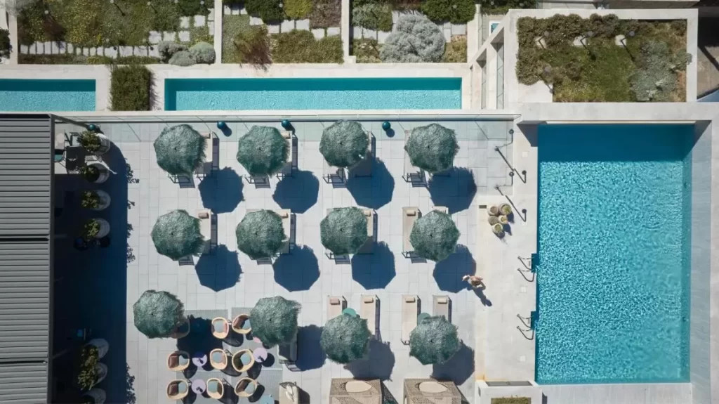 Diseño exterior simétrico con piscina, terrazas con sombrillas y áreas ajardinadas en Mallorca para esparcimiento