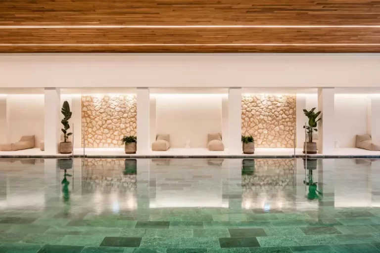 Diseño minimalista de piscina interior con nichos de piedra y mobiliario beige en Mallorca