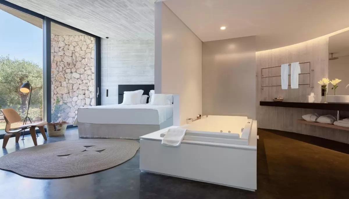 Diseño moderno de habitación con jacuzzi integrado y baño abierto en Mallorca con luz natural y acabados cálidos