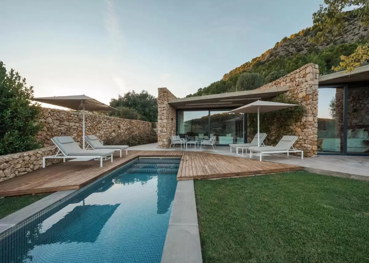 Diseño moderno de piscina y área exterior con piedra natural, madera y mobiliario en Mallorca