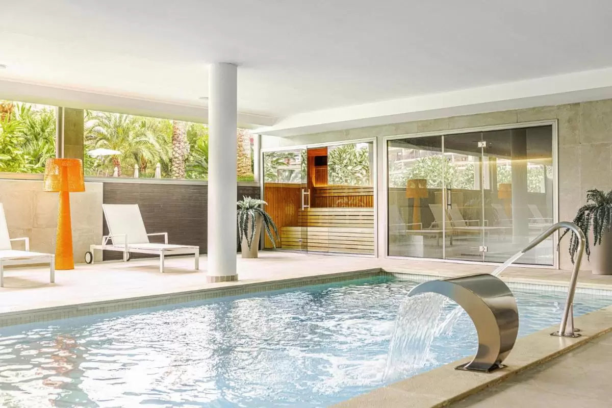 Diseño moderno y minimalista de piscina interior con sauna y vistas a la vegetación en Mallorca