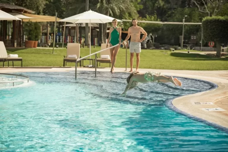 Escena al aire libre en piscina con niño saltando al agua y adultos observando en Mallorca