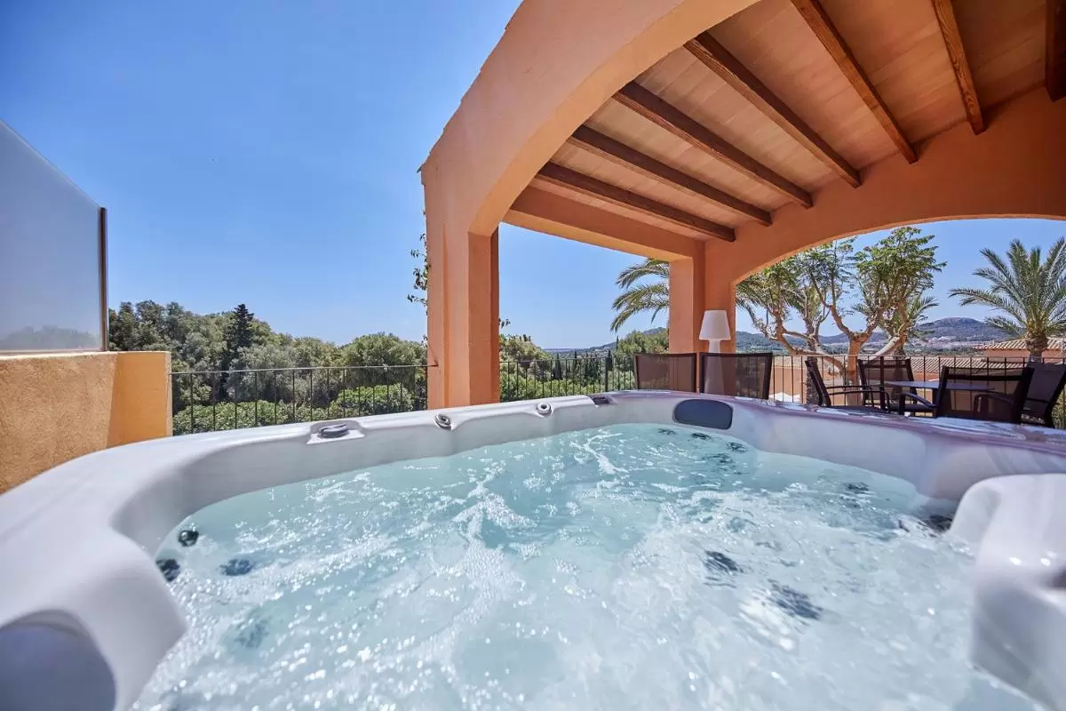 Espacio exterior con jacuzzi y muebles de terraza bajo techo de vigas de madera en Mallorca