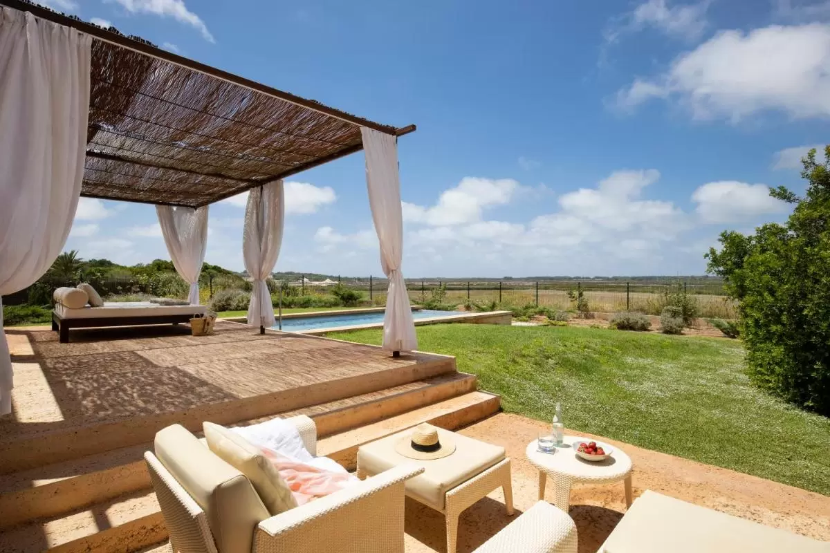 Espacio exterior con piscina, pérgola de cañas y mobiliario de jardín en Mallorca para relajación al aire libre