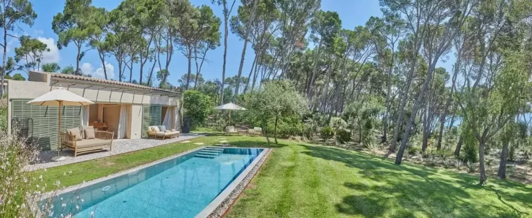 Espacio exterior con piscina rectangular, jardín cuidado y mobiliario de terraza en Mallorca soleada
