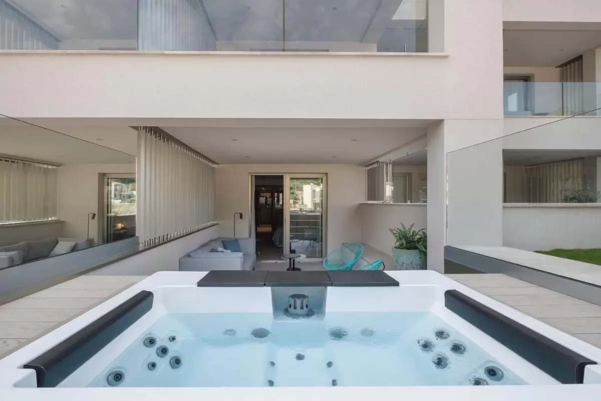 Espacio exterior moderno con jacuzzi rectangular, terraza cubierta y mobiliario contemporáneo en Mallorca