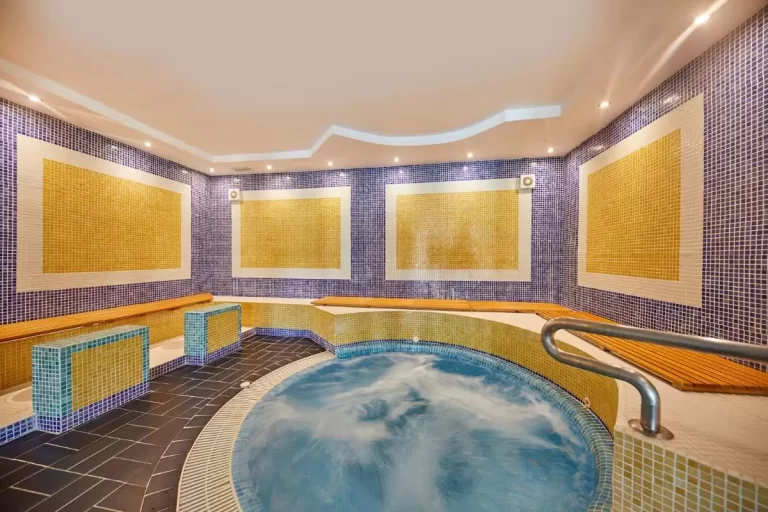 Espacio interior con jacuzzi circular y diseño de mosaicos en tonos azules y amarillos en Mallorca