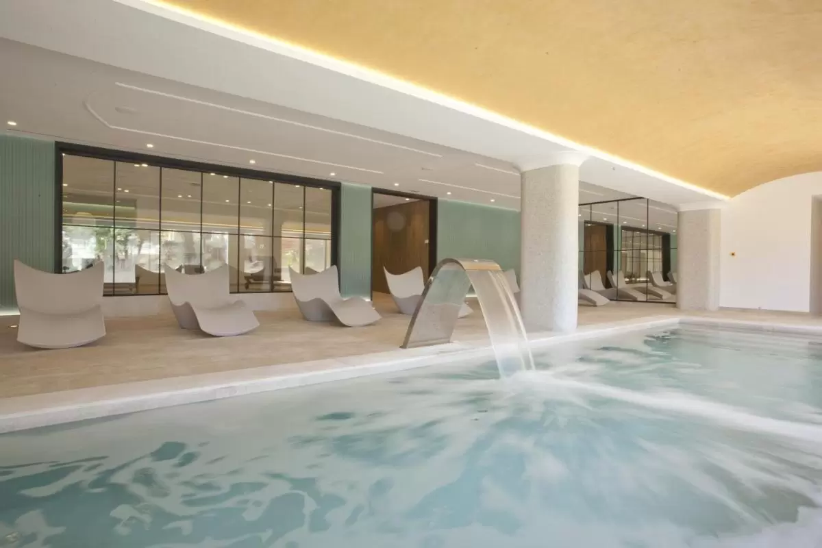 Espacio interior con piscina de spa, sillas reclinables modernas y techo abovedado iluminado en Mallorca