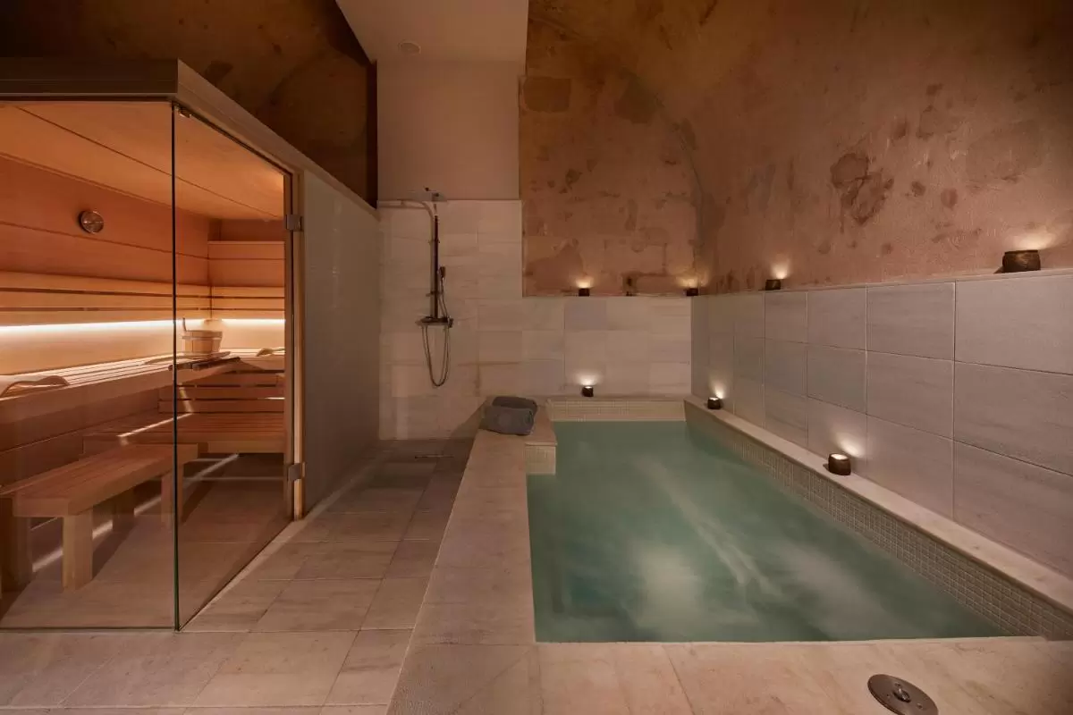 Espacio interior de bienestar con piscina, sauna de madera y ducha en ambiente cálido y relajante en Mallorca