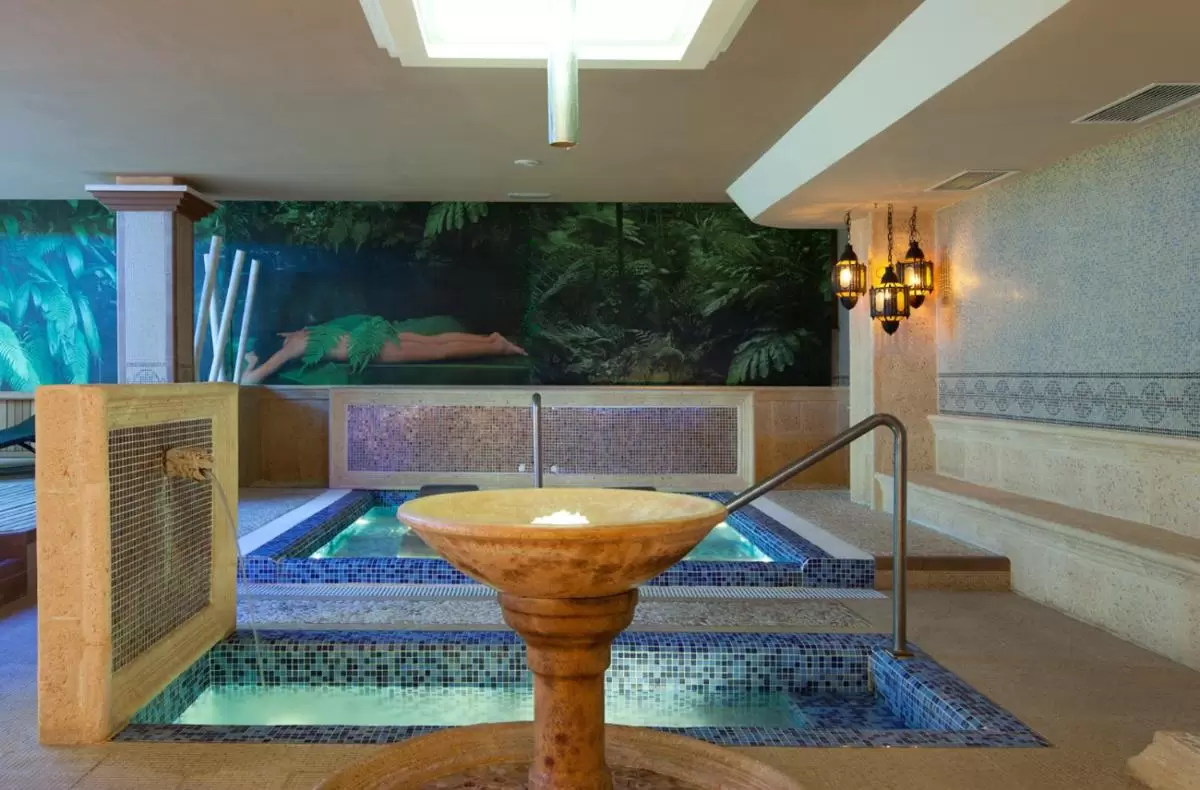 Espacio interior de hidroterapia con piscinas de mosaicos y ambiente natural en Mallorca