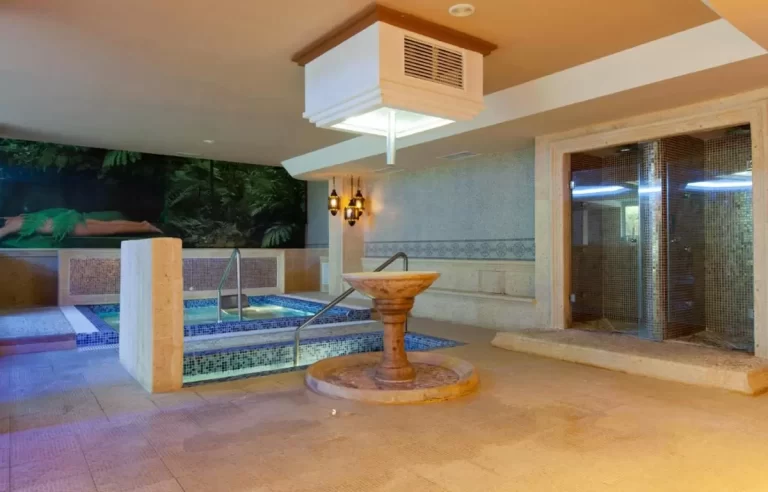 Espacio interior de hidroterapia en Mallorca con piscinas, fuente de piedra y sauna de mosaicos dorados
