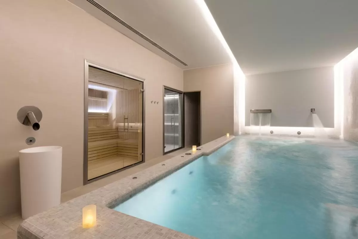 Espacio interior de relajación con piscina de hidromasaje, sauna de madera y fuente de agua en Mallorca