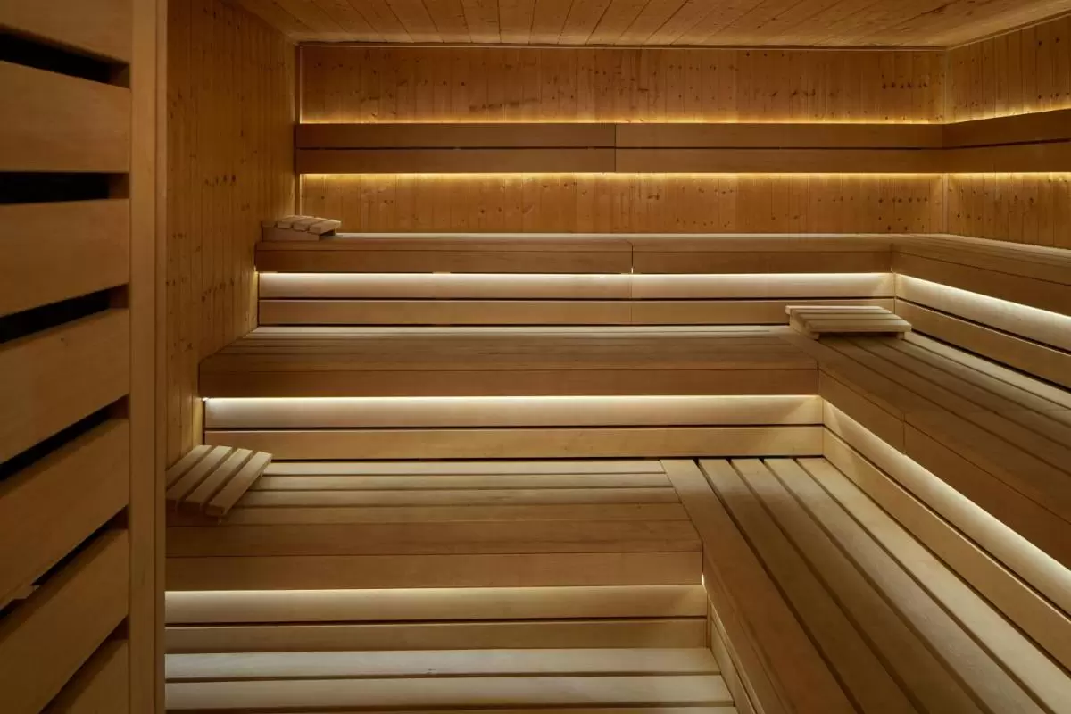 Interior de sauna de madera clara con bancos en forma de L y luz indirecta integrada en Mallorca