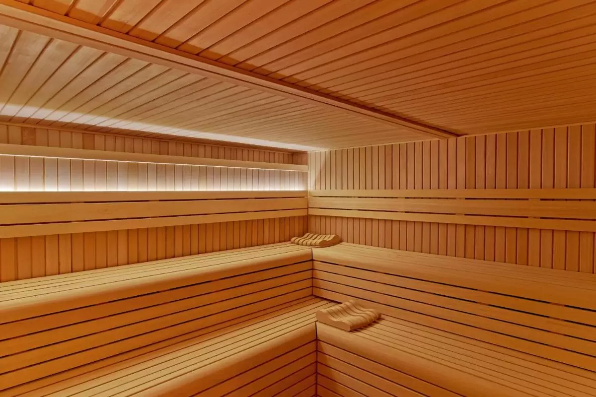 Interior de sauna de madera clara con bancos en L y luz cálida indirecta en Mallorca