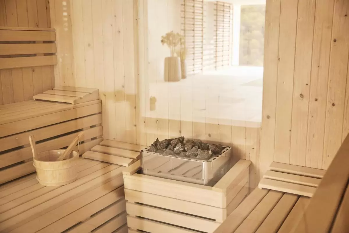 Zafiro Palace Andratx Interior de sauna de madera clara con calentador eléctrico y banco en L en Mallorca para relajación
