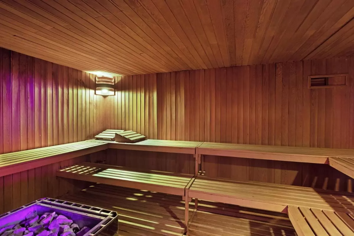 CM Mallorca Palace - Only Adults Interior de sauna de madera con bancos escalonados, lámpara cálida y calentador de piedras volcánicas en Mallorca