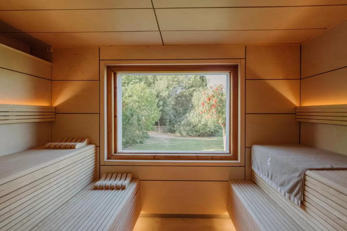 Interior minimalista y funcional de sauna de madera clara con iluminación cálida y ventana natural en Mallorca