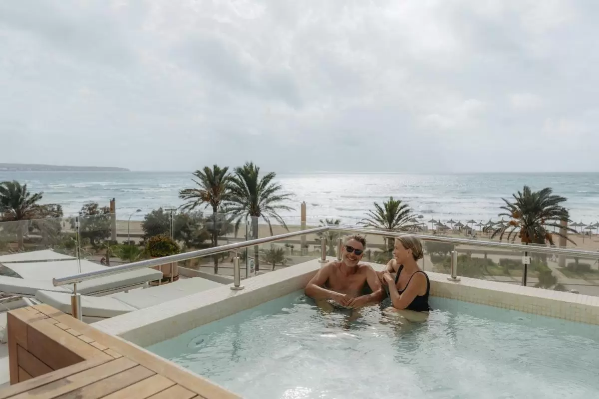 Jacuzzi en terraza con vista al mar y playa de Mallorca con palmeras y ambiente relajado