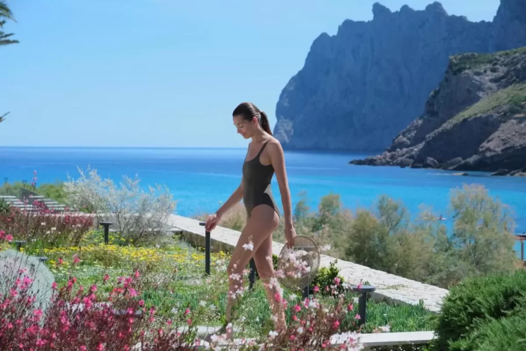 El Vicenç de la Mar - Adults Only - Over 12 Mujer caminando con traje de baño y sombrero de paja en entorno natural junto al mar en Mallorca