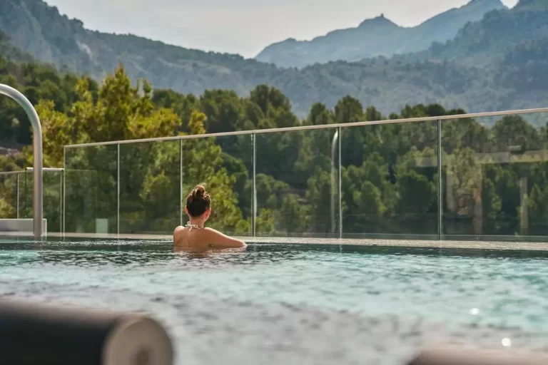 Persona disfrutando de una piscina al aire libre con vistas a colinas verdes en Mallorca durante el día