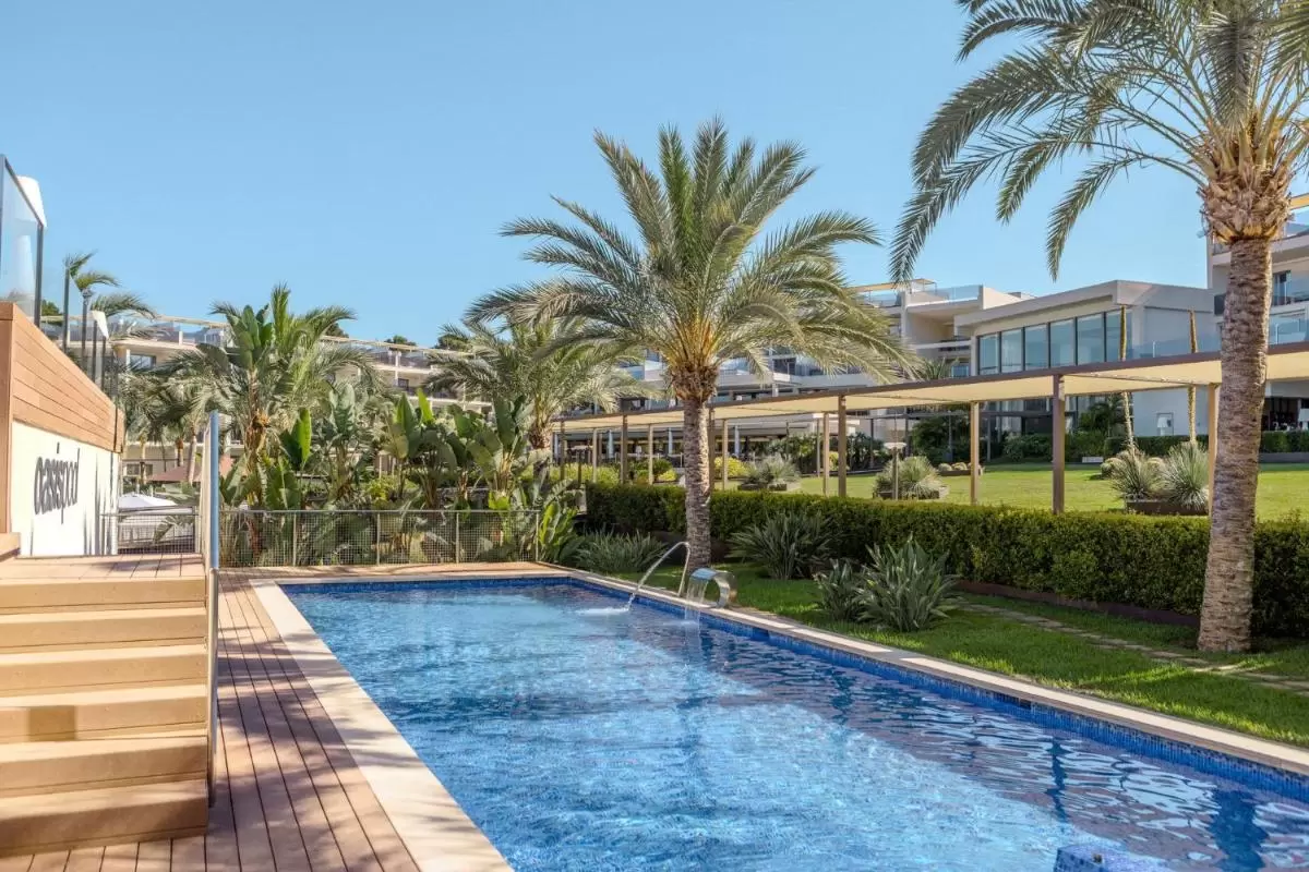 Piscina al aire libre con agua clara y azul rodeada de vegetación y estructuras modernas en Mallorca