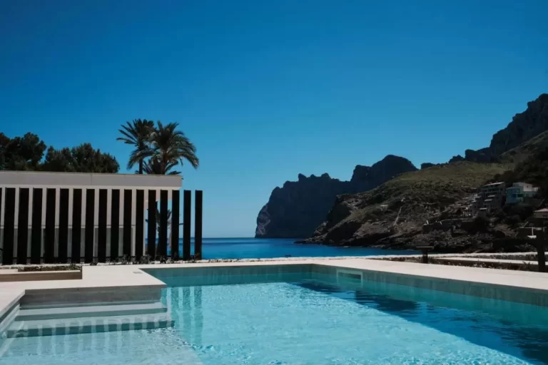 Piscina al aire libre con agua cristalina en terraza con vistas al mar y paisaje montañoso en Mallorca