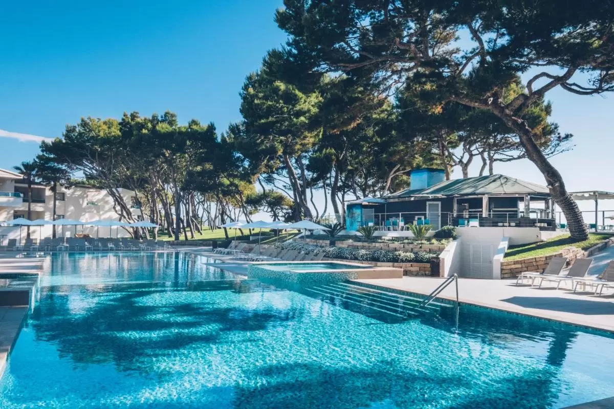 Piscina al aire libre con área de descanso hexagonal, tumbonas y entorno natural en Mallorca