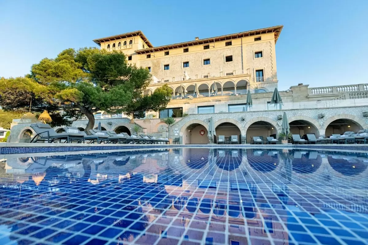 Piscina al aire libre con azulejos azul oscuro y líneas blancas en entorno arquitectónico con arcos y terraza en Mallorca