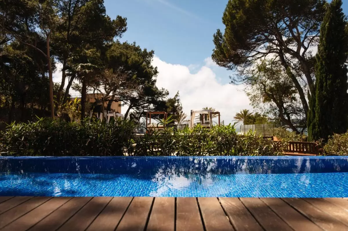 Piscina al aire libre con revestimiento de azulejos azules y deck de madera en Mallorca