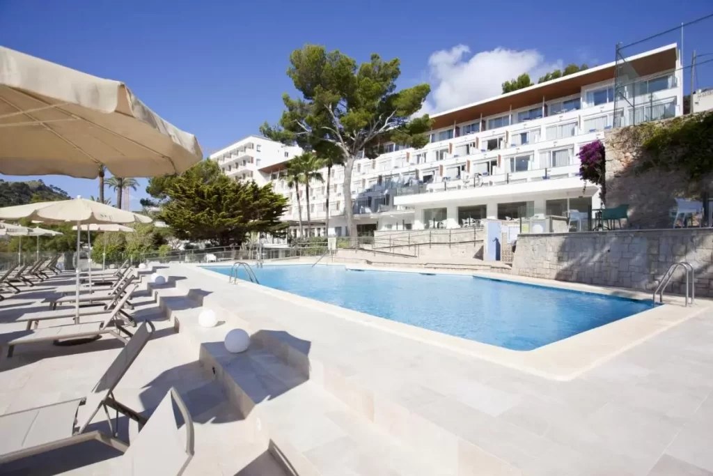 Piscina al aire libre con tumbonas y sombrillas en entorno moderno y soleado en Mallorca