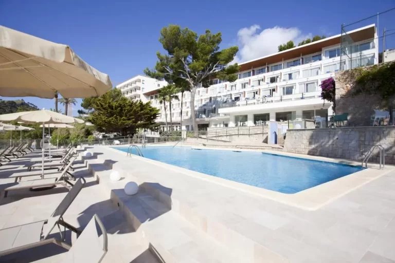 Piscina al aire libre con tumbonas y sombrillas en entorno moderno y soleado en Mallorca