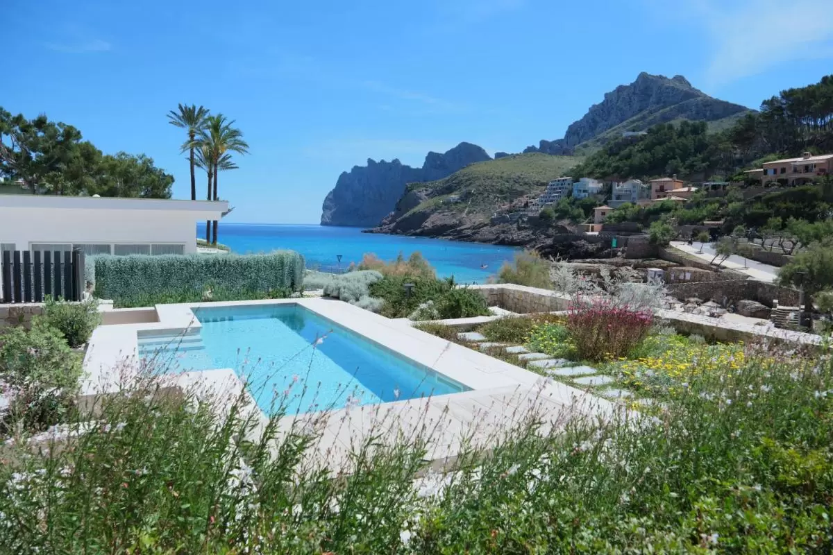 Piscina al aire libre con vistas al mar y entorno natural en zona costera de Mallorca con vegetación y arquitectura moderna