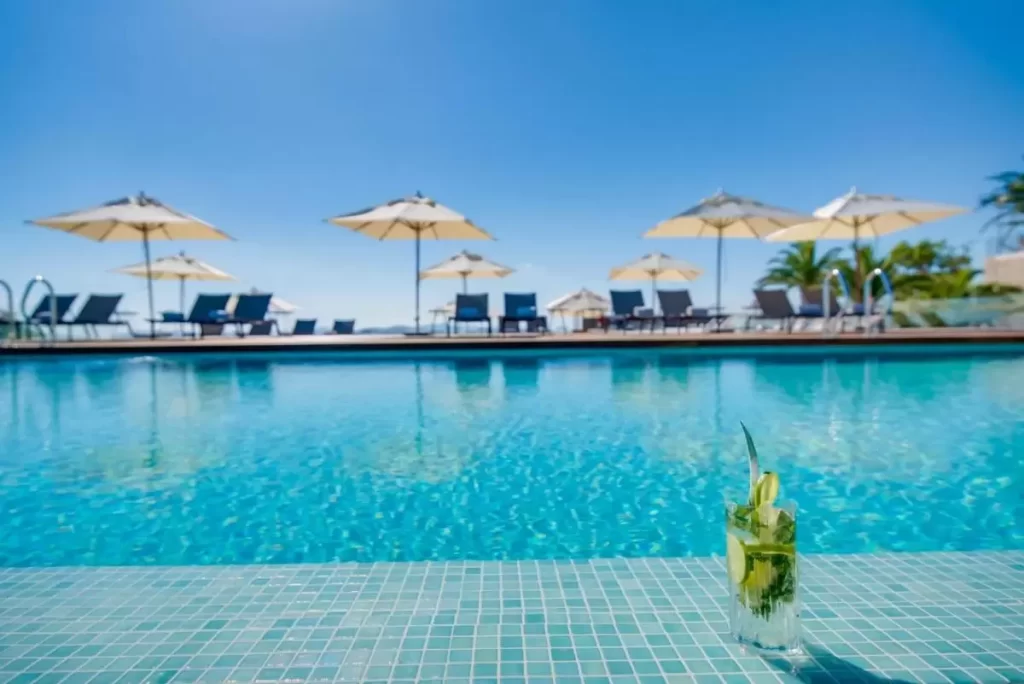 Piscina al aire libre en Mallorca con agua cristalina, borde de azulejos azules y bebida refrescante con limón y piña